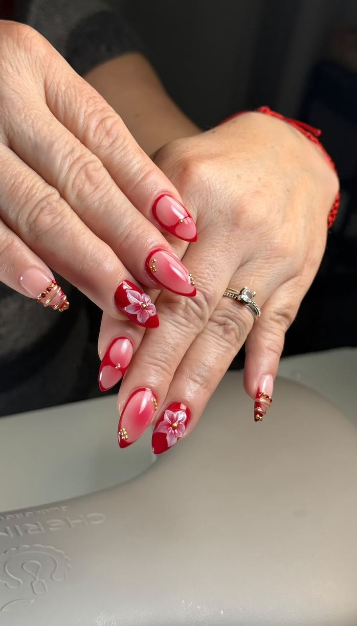Manicura con flores pintadas a mano sobre rojo cereza, trabajo de Divane Chick en Chillán